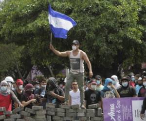 Un estudiante sostiene la bandera de Nicaragua sobre una barricada en protesta a las reformas hechas al Instituto Nicaragüense de Seguridad Social. AFP PHOTO / INTI OCON
