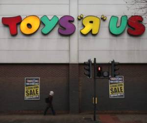 A pedestrian walks past a Toys 'R' Us store with 'closing down sale' signs in the windows in south London on February 9, 2018.The UK division of troubled toy retailer Toys R Us is up for sale with 25 stores already having closing down sales putting jobs at risk. / AFP PHOTO / Daniel LEAL-OLIVAS