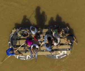 Aerial picture showing migrants and residents using a makeshift raft to cross the Suchiate river from Tecun Uman in Guatemala to Ciudad Hidalgo in Chiapas State, Mexico, on June 6, 2019. - The US warned Mexico Thursday it needed to make more concessions on slowing migration to avoid President Donald Trump's threatened tariffs, as the Mexican leader announced he would visit the border to 'defend our dignity.' Mexican authorities responded to one key US demand Wednesday by blocking the latest US-bound caravan of undocumented migrants as it entered Mexico from Guatemala. (Photo by Pedro PARDO / AFP)