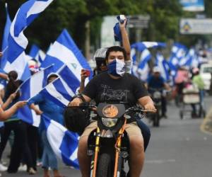A motorcycle rides as anti-government protesters stand forming a 'Human Chain' in Managua, on July 4, 2018.Thousands of Nicaraguans stood Wednesday forming a 'Human Chain' in the road linking Managua and Masaya in demand of Ortega's resignation and the end of violence which has left over 220 people killed in 75 days of protests. / AFP PHOTO / MARVIN RECINOS
