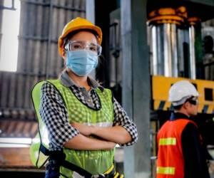 Factory woman worker or technician with hygienic mask stand with confident action with her co-worker as background.