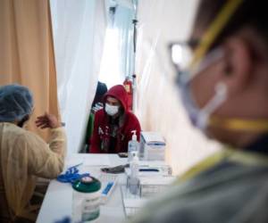 NEW YORK, NY - MARCH 20: A doctor examines Juan Vasquez for a COVID-19 test inside a testing tent at St. Barnabas hospital on March 20, 2020 in New York City. St. Barnabas hospital in the Bronx set-up tents to triage possible COVID-19 patients outside before they enter the main Emergency department area. Misha Friedman/Getty Images/AFP