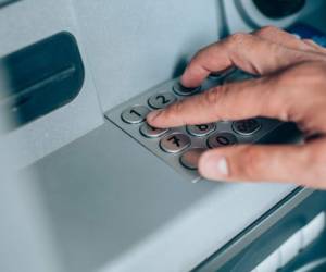 Close-up shot of man's hand withdrawing cash from ATM putting PIN entry