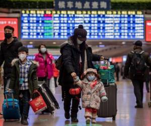 A girl (C), wearing a face mask, holds the finger of her mom and a lantern as they travel back home for the Lunar New Year holidays, at Beijing West Railway Station in Beijing on January 24, 2020. - Chinese authorities rapidly expanded a mammoth quarantine effort aimed at containing a deadly contagion on January 24 to 13 cities and a staggering 41 million people, as nervous residents were checked for fevers and the death toll climbed to 26. (Photo by NICOLAS ASFOURI / AFP)