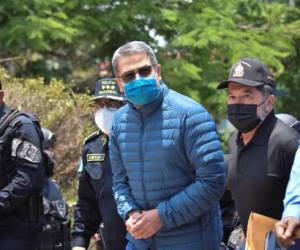 El expresidente de Honduras, Juan Orlando Hernandez (C), es custodiado por fuerzas de seguridad antes de ser extraditado a EEUU he US to face drug-trafficking related charges, in Tegucigalpa, on April 21, 2022. (Photo by STRINGER / AFP)