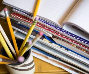 Stack of books or paperwork on desk. High angle view, pencils in holder in foreground.