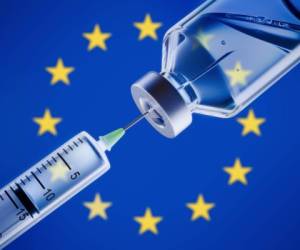 Closeup of a syringe and vaccine in front of European flag background