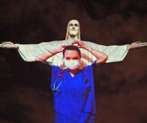 View of the world famous Christ the Redeemer statue on Easter day with a medical worker projected on it in honour of all the medical staff fighting the COVID-9 coronavirus pandemic worldwide in Rio de Janeiro, Brazil on April 12, 2020. (Photo by CARL DE SOUZA / AFP)