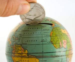 'A silver dollar being placed into an antique (1947) globe bank, symbolizes world banking, currency, exchange, etc.'