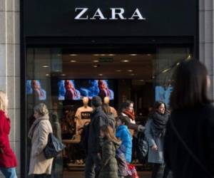 People pass by a Zara shop announcing discounts on the first day of the winter sales in Barcelona on January 7, 2017. / AFP PHOTO / JOSEP LAGO