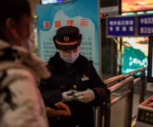 Un controlador ferroviario verifica la identificación de un viajero a su llegada a la estación principal de trenes de Wuhan el 10 de enero de 2021, la víspera del primer aniversario de China que confirma su primera muerte por el coronavirus Covid-19. (Foto de NICOLAS ASFOURI / AFP)