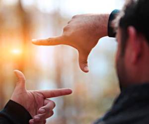 Man hands framing distant sun rays.