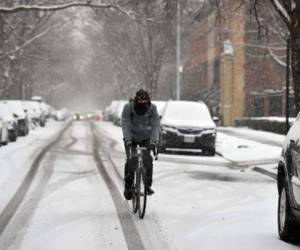 A cyclist rides through snow in the New York borough of Brooklyn during a winter storm on February 18, 2021. - A historic winter weather system that brought bitter, record-busting cold to much of the southern and central US was pushing up the East Coast on Thursday, with forecasters warning of heavy snowfall and dangerous, icy buildups. The frigid blast has over the past week seen Arctic cold envelope the US heartland unfamiliar with such extremes, leaving dozens of dead in its wake and millions of people in oil-rich Texas without power. (Photo by ANGELA WEISS / AFP)