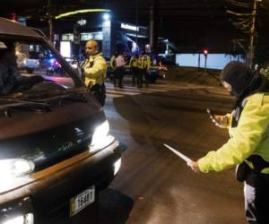 Costa Rican police officers control drivers at a check point during a transit operation following the decree that restricts vehicular traffic from 10 p.m. to 5 a.m. to prevent the spread of the Covid-19 in San Jose, Costa Rica, on March 25, 2020. (Photo by Ezequiel BECERRA / AFP)