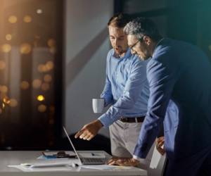 Shot of a coworkers using a laptop together while woking late at the office