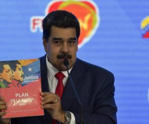 Venezuela's president Nicolas Maduro shows a document called 'Plan de La Patria' while delivering a speech during the closing ceremony of the International Turism Fair at the Bolivar Park in Caracas, Venezuela on November 26, 2018. (Photo by YURI CORTEZ / AFP)