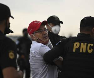 Guatemala's former guerrilla commander Cesar Montes is escorted by police officers upon arrival at the Air Force Base in Guatemala City on October 10,2020. - Former Guatemalan guerrilla commander Cesar Montes was arrested Saturday in Mexico on charges of killing three soldiers in 2019, an event that led his country's government to decree a 'state of siege' in 22 municipalities and declare him Guatemala's most wanted man. (Photo by Johan ORDONEZ / AFP)