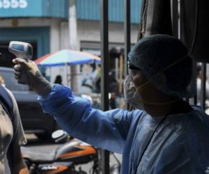 A health worker checks the body temperature of a man as he enters the Soyapango municipal market to buy food on April 21, 2020 in Soyapango, El Salvador. (Photo by Yuri CORTEZ / AFP)