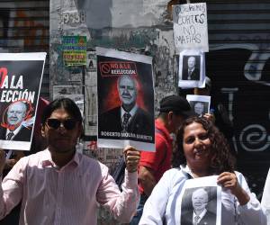 <i>Personas sostienen carteles con la imagen del abogado Roberto Molina Barreto durante una manifestación este jueves, en Ciudad de Guatemala (Guatemala). Según diversas fuentes, la elección parlamentaria podría favorecer a figuras cuestionadas como Roberto Molina Barreto, vinculado a la excandidata presidencial Zury Ríos, y a la fiscal general Consuelo Porras, sancionada por EE. UU. y la Unión Europea. EFE/ Alex Cruz</i>