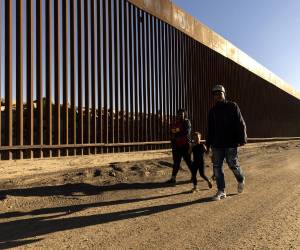 <i>Fotografía de archivo del 28 de octubre de 2022 de una familia caminando junto al muro fronterizo en Yuma, Arizona(Estados Unidos). Estados Unidos anunció este viernes la terminación de programas migratorios humanitarios de reunificación familiar para nacionales de Colombia, Cuba, Ecuador, El Salvador, Guatemala, Haití y Honduras, así como para sus familiares inmediatos, argumentando abusos de estas protecciones. EFE/EPA/ Etienne Laurent / ARCHIVO</i>