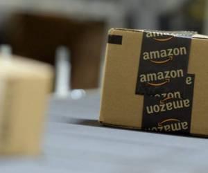 An employee carries a package at the distribution center of US online retail giant Amazon in Moenchengladbach, on December 17, 2019. (Photo by INA FASSBENDER / AFP)