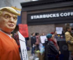 Un activista protesta con una máscara del presidente Donald Trump y con un traje de preso fuera de un Starbucks en Philadelphia, Pennsylvania.