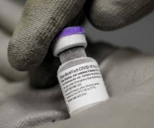 A picture taken on January 15, 2021, shows a pharmacist holding with gloved hands a phial of the undiluted Pfizer-BioNTech vaccine for Covid-19, stored at -70 ° in a super freezer of the hospital of Le Mans, northwestern France as the country carry on a vaccination campaign to fight against the spread of the novel coronavirus. - US pharma group Pfizer warned that Covid-19 vaccine deliveries to Norway and Europe would be reduced 'as of next week' as the company ramps up its production capacity, Norwegian health authorities said. (Photo by JEAN-FRANCOIS MONIER / AFP)