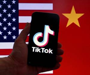 En esta ilustración fotográfica, el logotipo de la aplicación de redes sociales TikTok se muestra en la pantalla de un iPhone frente a una bandera estadounidense y un fondo de bandera china en Washington, DC, el 16 de marzo de 2023. FOTO OLIVIER DOULIERY / AFP