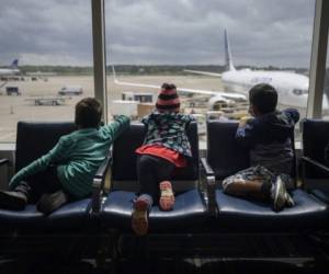 Los hermanos Dariel (L)] y Diana (C) de Honduras se sientan con Daniel (R) de El Salvador en el aeropuerto de Houston durante una transferencia el 30 de marzo de 2021 después de ser liberados de un centro de detención del gobierno de EE. UU. Para migrantes ilegales que buscan asilo en McAllen. Texas. 'Por favor ayúdenme, no hablo inglés', dice un sobre manila en grandes letras negras con el que decenas de familias indocumentadas de Guatemala y Honduras llegan diariamente al aeropuerto de McAllen, Texas, el primero al que han entrado en sus vidas. Es la última etapa de un largo viaje en el que han arriesgado la vida para huir de Centroamérica en bus, auto, tráiler, a pie y finalmente en bote por el Río Bravo desde México a Estados Unidos, conducidos por coyotes a lo largo de una carretera. controlado por los cárteles de la droga.Ed JONES / AFP