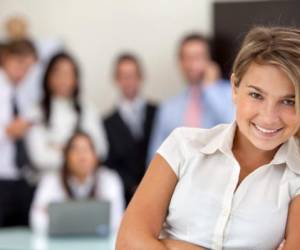 Business woman smiling with her team behind her at the office