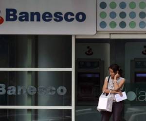 A woman stands at the entrance of a Banesco bank office in Caracas on May 4, 2018. After Venezuela arrested the president of Banesco, the country's leading private bank, along with 10 top executives on suspicion of 'attacks' on the local currency, the government decided to intervene the bank for 90 days. / AFP PHOTO / Luis ROBAYO