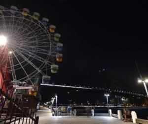 The Sydney Harbour Bridge, the Opera House and the ferris wheel are seen after their lights went out as seen from Sydney's Luna Park for the Earth Hour environmental campaign on March 30, 2019. - The lights went out on two of Sydney's most famous landmarks for the 12th anniversary of the climate change awareness campaign Earth Hour, among the first landmarks around the world to dim their lights for the event. (Photo by PETER PARKS / AFP)