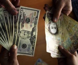 Photo showing US dollar and Venezuelan Bolivares notes in Caracas on July 16, 2013. In a country with strict currency exchange control since 2003, Venezuelans in urgent need of dollars to travel lined up on banks Tuesday --the deadline to buy dollars for the first time at an auction-- looking forward to get more currency than the allowed, despite being at a higher rate than the official. AFP PHOTO / JUAN BARRETO / AFP PHOTO / JUAN BARRETO