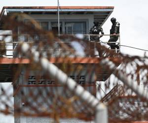 <i>Elementos de la Policía Militar de Orden Público (PMOP) vigilan desde una torre de vigilancia la presentación a la prensa de armas, municiones, drogas, teléfonos móviles y otros elementos incautados durante un operativo en la Penitenciaría Nacional “Francisco Morazán” en el penal de Tamara, 25 km al norte de Tegucigalpa, el 26 de junio de 2023. (Foto de Orlando SIERRA / AFP)</i>