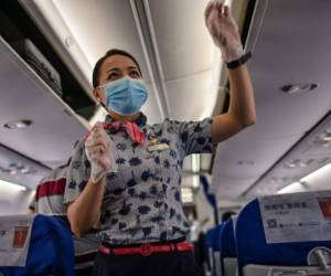 A flight attendant wearing a facemask walks in a plane's alley of a flight to Shanghai at Tianhe Airport in Wuhan, in Chinas central Hubei province on May 29, 2020. - China's foreign minister on May 24 said the country was 'open' to international cooperation to identify the source of the disease, but any investigation must be led by the World Health Organization and 'free of political interference'. (Photo by Hector RETAMAL / AFP)