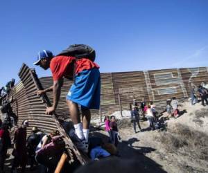 A group of Central American migrants -mostly Hondurans- climb a metal barrier on the Mexico-US border near El Chaparral border crossing, in Tijuana, Baja California State, Mexico, on November 25, 2018. - US officials closed the San Ysidro crossing point in southern California on Sunday after hundreds of migrants, part of the 'caravan' condemned by President Donald Trump, tried to breach a fence from Tijuana, authorities announced. (Photo by Pedro PARDO / AFP)
