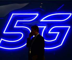 A man speaks on the phone next to a 5G hotspot sign displayed at the Mobile World Congress (MWC) in Barcelona on February 25, 2019. - Phone makers will focus on foldable screens and the introduction of blazing fast 5G wireless networks at the world's biggest mobile fair starting February 25 in Spain as they try to reverse a decline in sales of smartphones. (Photo by GABRIEL BOUYS / AFP)