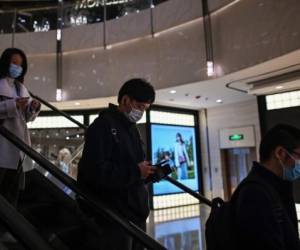 Las personas que usan mascarillas como medida preventiva contra el coronavirus Covid-19 usan un escaltor mecánico en un centro comercial en el distrito financiero de Lujiazu en Shanghai el 9 de noviembre de 2020 (Foto de Hector RETAMAL / AFP)