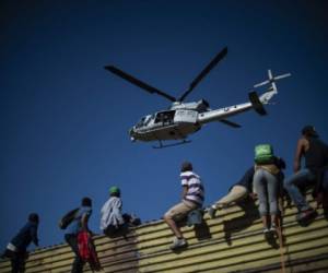 A group of Central American migrants climb the border fence between Mexico and the United States, near El Chaparral border crossing, in Tijuana, Baja California State, Mexico, on November 25, 2018. - Hundreds of migrants attempted to storm a border fence separating Mexico from the US on Sunday amid mounting fears they will be kept in Mexico while their applications for a asylum are processed. An AFP photographer said the migrants broke away from a peaceful march at a border bridge and tried to climb over a metal border barrier in the attempt to enter the United States. (Photo by Pedro PARDO / AFP)