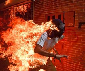 (FILES) This file photo taken on May 3, 2017 of a demonstrator catching fire during clashes with riot police within a protest against Venezuelan President Nicolas Maduro in Caracas, by AFP Venezuelan photographer Ronaldo Schemidt won the World Press Photo (WPP) picture of the Year 2018 award and 1st prize in the Spot News Singles category in Amsterdam on April 12, 2018. / AFP PHOTO / RONALDO SCHEMIDT
