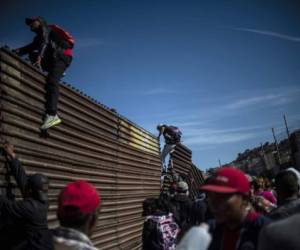 A group of Central American migrants -mostly Hondurans- climb the border fence between Mexico and the United States, near El Chaparral border crossing, in Tijuana, Baja California State, Mexico, on November 25, 2018. - Hundreds of migrants attempted to storm a border fence separating Mexico from the US on Sunday amid mounting fears they will be kept in Mexico while their applications for a asylum are processed. An AFP photographer said the migrants broke away from a peaceful march at a border bridge and tried to climb over a metal border barrier in the attempt to enter the United States. (Photo by Pedro PARDO / AFP)