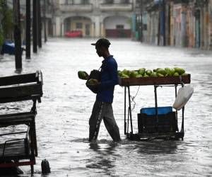 <i>Un hombre vende frutas en una calle inundada de La Habana, el 29 de agosto de 2023, durante el paso de la tormenta tropical Idalia. La tormenta tropical Idalia se fortaleció hasta convertirse en huracán este martes y los meteorólogos pronostican que se volverá extremadamente peligrosa antes de tocar tierra el miércoles en Florida, Estados Unidos. (Foto de Yamil LAGE / AFP)</i>
