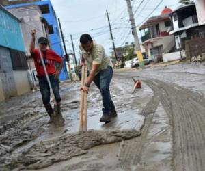 A man removes the mud left by the flooding after the rains related to the passage of Hurricane Maria, in Toa Baja, Puerto Rico, on September 22, 2017.Puerto Rico battled dangerous floods Friday after Hurricane Maria ravaged the island, as rescuers raced against time to reach residents trapped in their homes and the death toll climbed to 33. Puerto Rico Governor Ricardo Rossello called Maria the most devastating storm in a century after it destroyed the US territory's electricity and telecommunications infrastructure. / AFP PHOTO / HECTOR RETAMAL