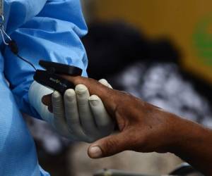 A health worker checks the oxygen level and the cardiac frequency of a COVID-19 patient at the tents outside the School Hospital in Tegucigalpa on July 6, 2020. - Honduras is facing and increase of COVID-19 cases and deaths with and average of 50 deaths a day. The public and private Health system is collapsed and with few resources to do diagnostic tests. (Photo by ORLANDO SIERRA / AFP)