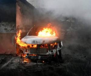 Vista de un auto en llamas en el parqueo del Congreso de Guatemala. (Photo by JOHAN ORDONEZ / AFP)