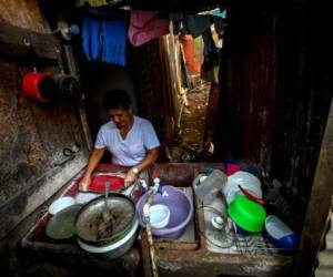 Sonia Zúñiga washes the dishes at her home in El Erizo neighbourhood, in the province of Alajuela, Costa Rica, on January 4, 2022. - Costa Rica, one of the most stable democracies in Latin America, which will elect its president on February 6, has been affected by poverty. According to the Community of Latin American and Caribbean States (CELAC), it is one of the countries in the region, along with Brazil, where more people will fall into poverty, due to the cutback of government aid and the effects of the pandemic. (Photo by Luis ACOSTA / AFP) / TO GO WHIT AFP STORY BY DAVID GOLDBERG