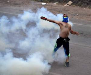 Un manifestante lanza una piedra a la policía venezuela en la frontera, con Pacaraima, Roraima, Brasil, el 23 de febrero de 2019. (Photo by Nelson ALMEIDA / AFP)