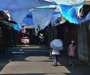 People walk across an empty street amid the 'absolute curfew' ordered by the Honduran government to slow the spread of the new coronavirus, COVID-19 in Tegucigalpa on April 4, 2020. - The number of people infected with COVID-19 reached 264 and 15 deaths, in the Central American country. (Photo by ORLANDO SIERRA / AFP)