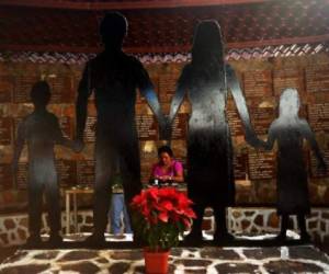 A woman puts a candel at the memorial hall of the massacre victims in the village of El Mozote, 220 kms north-east of San Salvador, El Salvador on January 15, 2012. More Than 900 people were killed in a massacre by the Salvadorean army in December 1981. On January 16th El Salvador will conmemorate the 20th anniversary of the peace agreement that ended the civil war from 1980 to 1992. AFP PHOTO/ Jose CABEZAS / AFP PHOTO / Jose CABEZAS