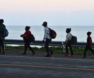 Honduran migrants walk along a road bordering the Caribbean sea in Omoa, going from San Pedro Sula to Corinto, Honduras, in the border with Guatemala, as part of a new caravan heading to the US, on January 15, 2020 early morning. - Some 1,000 Hondurans started a new caravan from San Pedro Sula, in the north of Honduras, to the US, in search of the 'American dream' and fleeing unemployment and violence. At least 30,000 Honduran migrants of the first caravans remain in Mexico waiting for US asylum. (Photo by ORLANDO SIERRA / AFP)